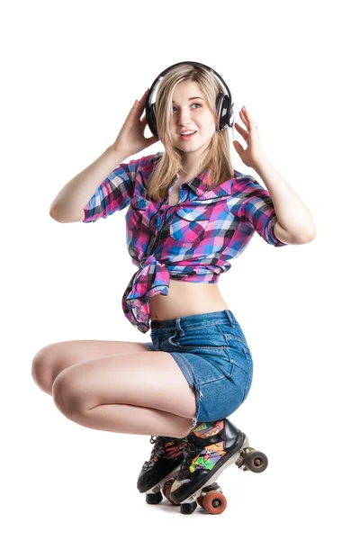 Радісна молода дівчина в роликових ковзанах і навушниках. Їздити і слухати музику. Веселий сміх . — стокове фото