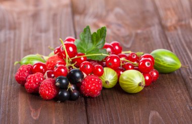 Ahşap bir masa üzerinde olgun çilek karışımı. Yaz natürmort. Ahududu, bektaşi, kuş üzümü yakın çekim.