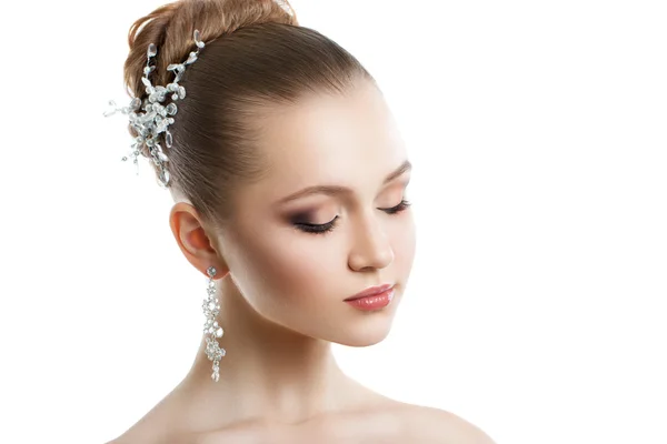 Retrato de una joven con maquillaje de boda. Piel perfecta, pelo liso, grandes pendientes de cristal y adorno para el cabello. Aislamiento sobre fondo blanco . — Foto de Stock