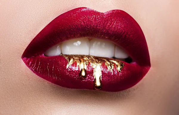 Beautiful female lips closeup. Red lipstick, gold paint flowing over his lips. Stock Photo Cosmetic Advertising — Stock Photo, Image