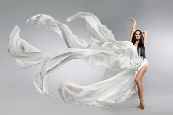Schöne junge Mädchen in fliegendem weißen Kleid. fließender Stoff. Leichtes weißes Tuch fliegt im Wind — Stockfoto