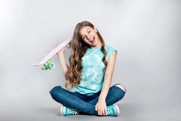 Chica posando con monopatín sentado en el estudio. Alegría, sonrisa, emociones positivas —  Fotos de Stock