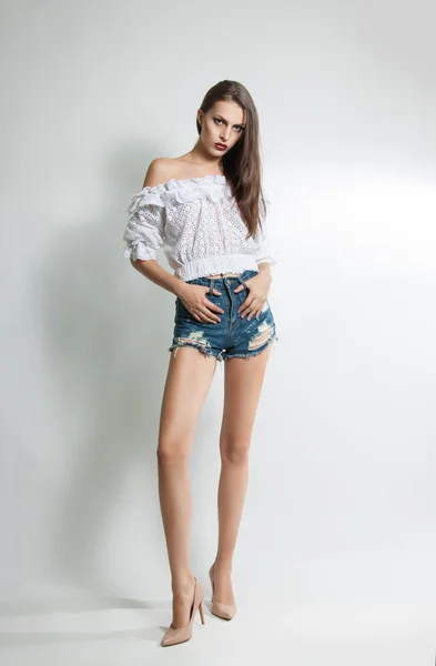 Joven hermosa chica en pantalones cortos y blusa posando en el estudio —  Fotos de Stock