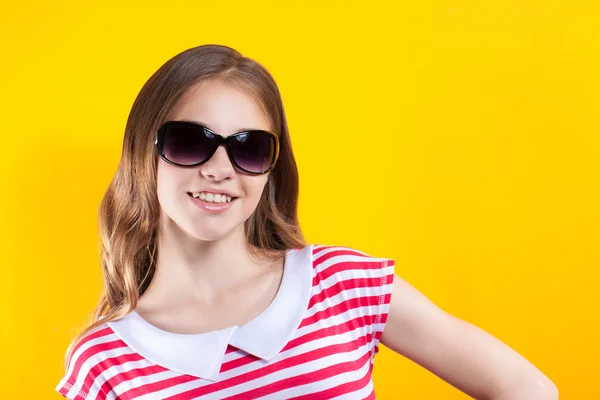 Hübsches Mädchen mit Sonnenbrille posiert auf gelbem Hintergrund. Helle Aktienfotos. positive menschliche Emotionen — Stockfoto