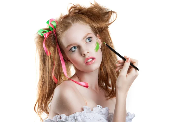 Schöne rothaarige Mädchen mit Bändern in volosah.kreativnaya Frisur und Make-up. ein Mädchen hält einen Pinsel und malt — Stockfoto