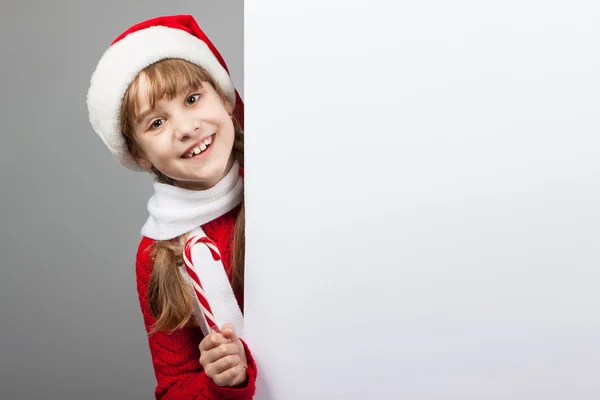 Menina feliz em santa claus chapéu segurando um pôster — Fotografia de Stock