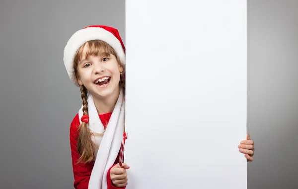 Směje se dívka v klobouku santa claus drží plakát — Stock fotografie