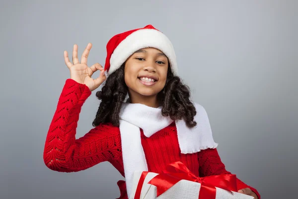 Menina com um presente de Ano Novo. Menina alegre em um boné de Papai Noel — Fotografia de Stock