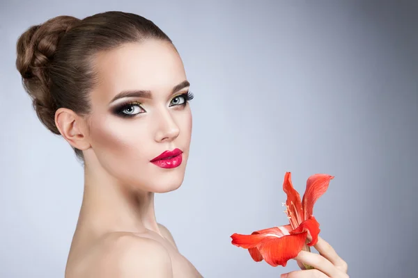 Mulher bonita com maquiagem brilhante e flor vermelha — Fotografia de Stock