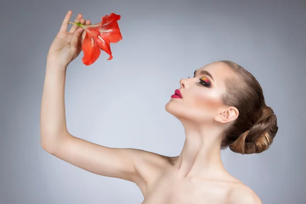 Mulher bonita com maquiagem brilhante e flor vermelha — Fotografia de Stock