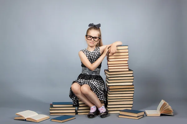 Menina inteligente com uma pilha de livros . — Fotografia de Stock