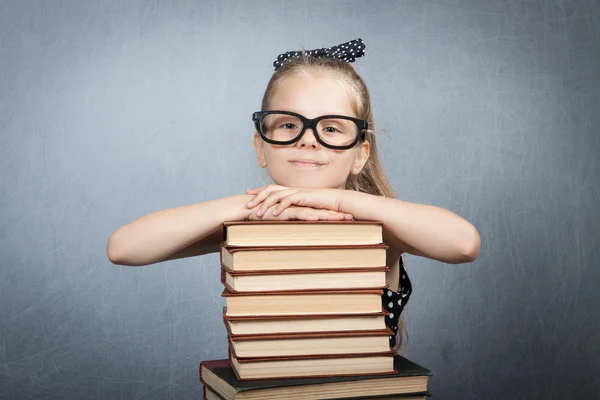 Chica inteligente con una pila de libros . — Foto de Stock