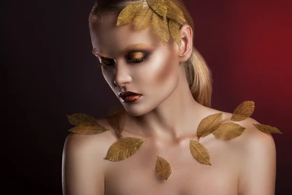 beautiful  woman in accessories with gold leaves