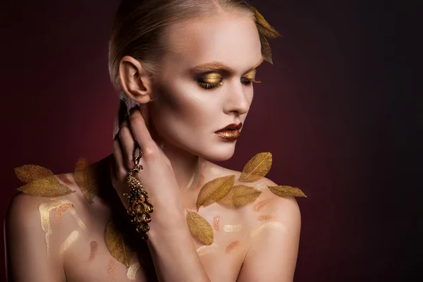 Красивая женщина в аксессуарах с золотыми листьями — стоковое фото