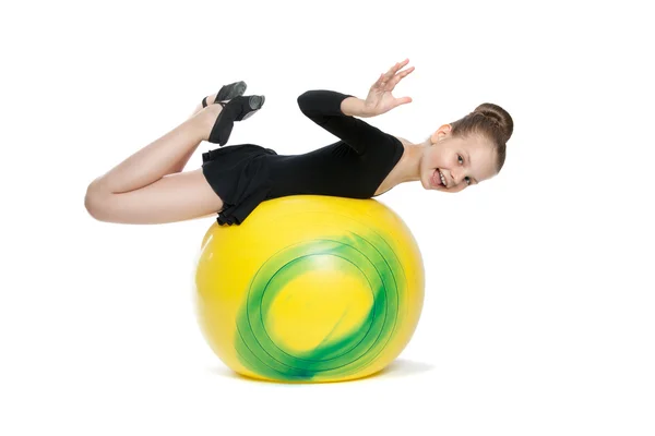 Menina faz exercícios em um grande balão amarelo — Fotografia de Stock