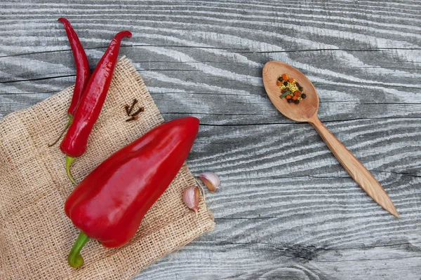 Pimenta vermelha e legumes na textura de madeira — Fotografia de Stock
