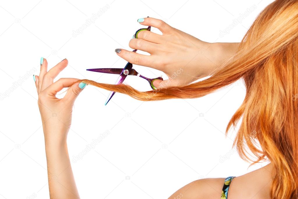 Long-haired red-haired girl with scissors cuts the hair