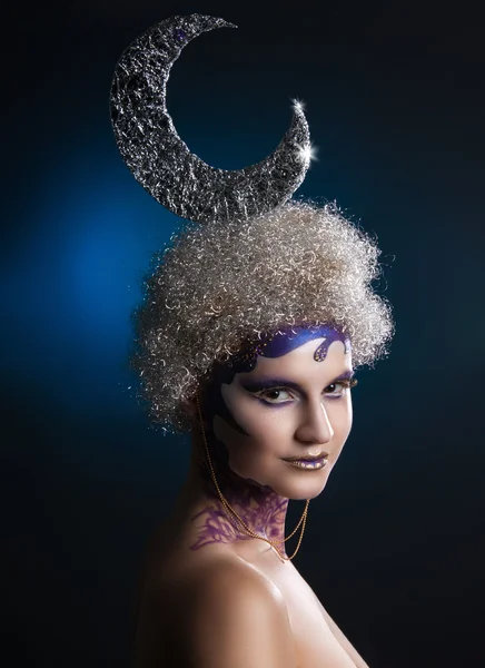 Retrato de inverno de uma menina com maquiagem criativa em um fundo azul escuro. Lua prateada de cabelo prateado em cachos. Roxo - Maquiagem de ouro . — Fotografia de Stock