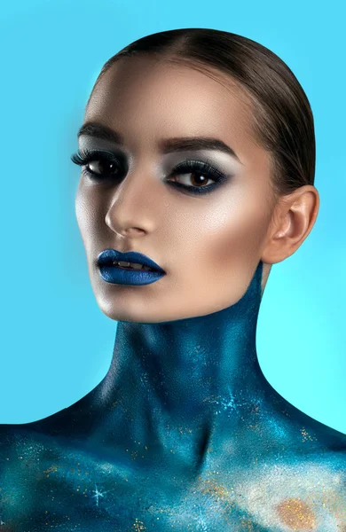 beautiful girl face painted with blue paint with glitter. Stock Photo