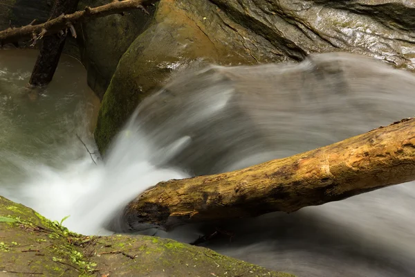 Beautiful smooth flowing stream with a small waterfall — Stock Photo, Image
