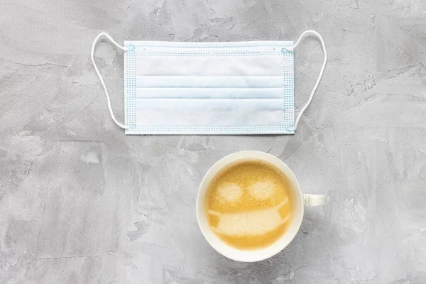 Fehér orvosi maszk és egy csésze kávé — Stock Fotó