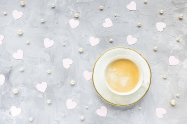 Açık gri arka planda, kalpleri olan bir fincan kahve.