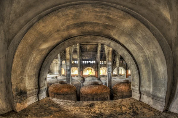 View through arch of concrete fermentation tanks in an abandoned — Stock Photo, Image