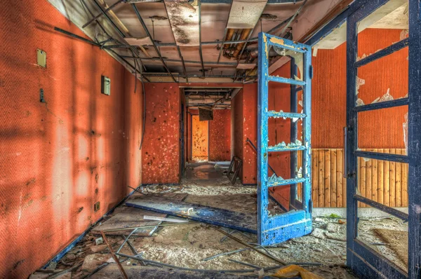 Porte bleue dans un couloir rouge délabré d'un hôtel abandonné — Photo