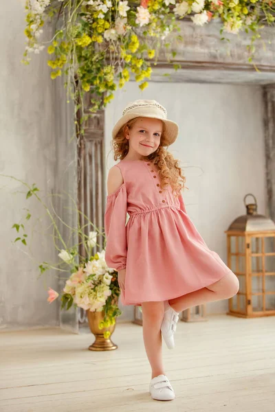 美しいです女の子でお祝いピンクのドレス 帽子と白いスニーカーポーズでスタジオ — ストック写真