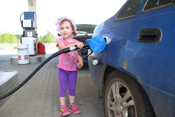 Kız arabaya benzin dolduruyor.