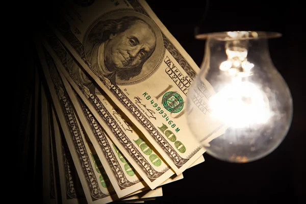Ampoule suspendue pendue sur un fil éclairant les billets de banque — Photo