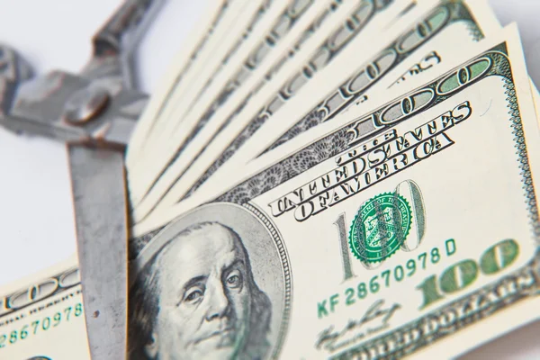 Ножиці вирізають банкноту доларів на білому тлі — стокове фото