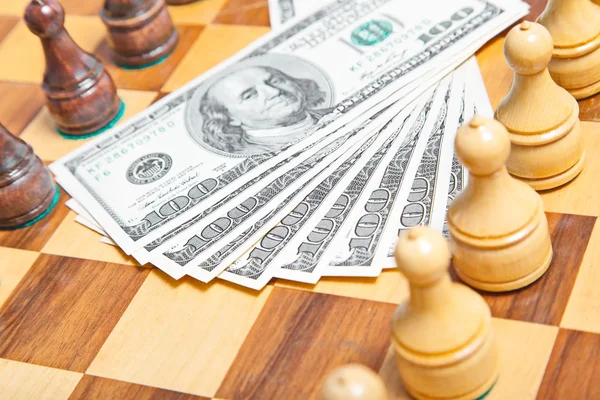 Dollari USA e cifre scacchistiche su una vecchia scacchiera di legno — Foto Stock