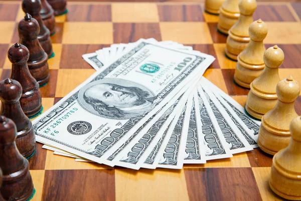 Dollari USA e cifre scacchistiche su una vecchia scacchiera di legno — Foto Stock