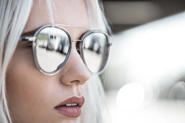 Schöne blonde Mädchen mit grauer Sonnenbrille im Freien lizenzfreie Stockbilder