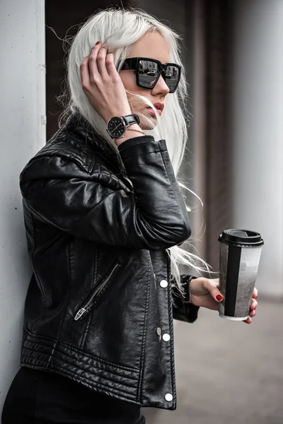Mladá blondýnka pózuje s kávou venku — Stock fotografie