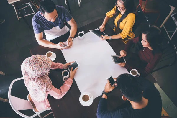 Amigos en un restaurante con dispositivos digitales — Foto de Stock