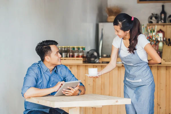 Asyalı garson kahve servisi yapıyor.