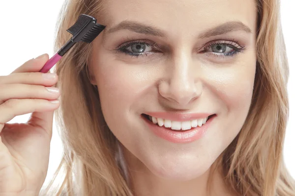 Mujer rubia usando peine de cejas — Foto de Stock