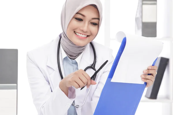 Asian female doctor with stethoscope reading a note — Stock Photo, Image