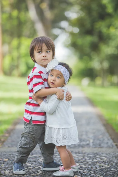 Pequeño niño abrazando chica en parque — Foto de Stock