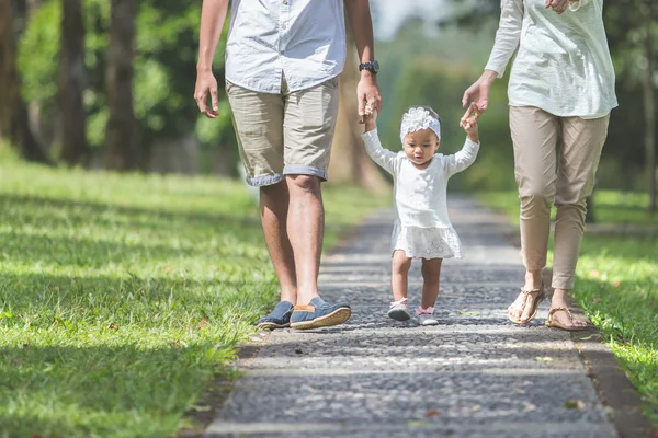 Bebê aprender a andar pela primeira vez com seus pais segurá-la — Fotografia de Stock