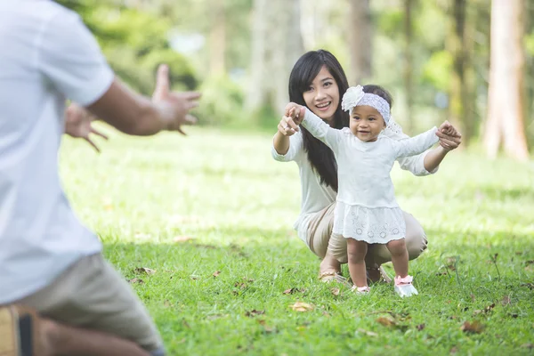 Bambino imparare a camminare con i loro genitori nel parco — Foto Stock