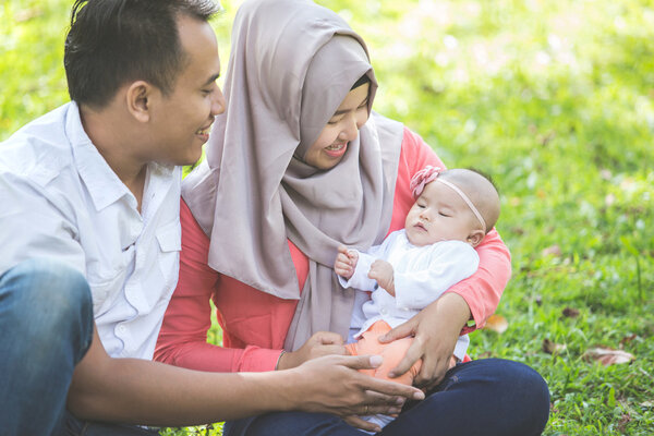 семья с новорожденным ребенком в парке
