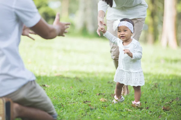 Bebê feliz fazendo seus primeiros passos em uma grama verde — Fotografia de Stock