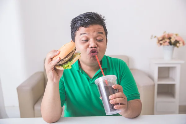 Człowiek, cieszyć się w domu jedzenie hamburgerów — Zdjęcie stockowe
