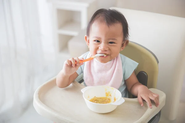 Baby girl sitting on high chair and feed her self — Stock Photo, Image