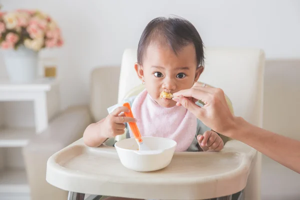 Felice giovane bambino in seggiolone essere alimentato — Foto Stock