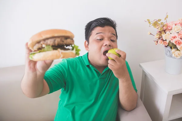 Homem com sobrepeso escolhendo maçã fresca saudável em vez de junk food — Fotografia de Stock