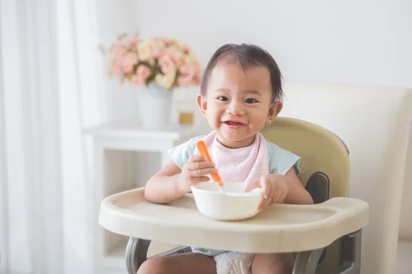 Bambina seduta sul seggiolone e nutrire se stessa — Foto Stock